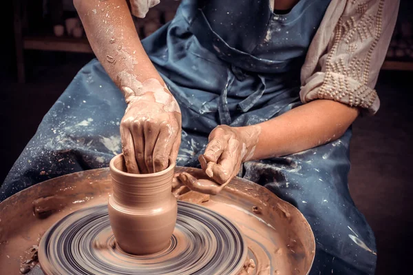 Close-up Een vrouwelijke pottenbakker in prachtig gebeeldhouwd een diepe kom bruine klei en snijdt overtollige klei af op een pottenbakkerswiel in een prachtige werkplaats — Stockfoto