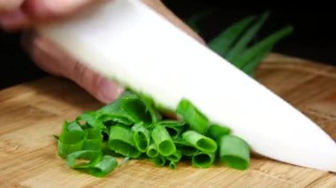 Tahtada keskin bir bıçakla yeşil soğan dilimlemek.