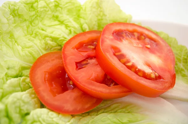 Red tomatoe slices on lettuce leaves — Stock Photo, Image