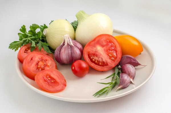 Tomatoes, garlic, onions and greens on a plate — Stock Photo, Image