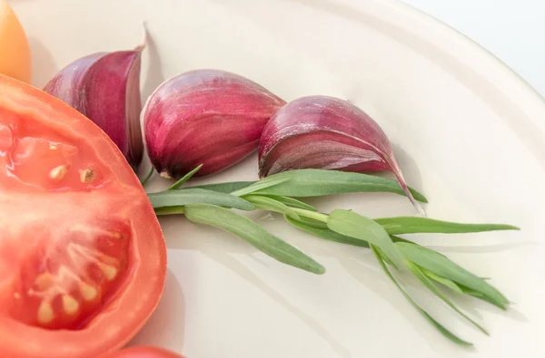 Fresh circle of a tomato, garlic and greens  on a plate