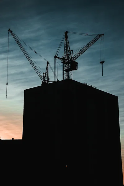 Силуэт башенного крана на фоне городского строительства — стоковое фото