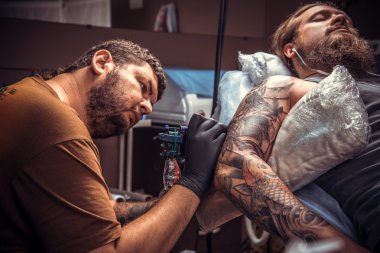 Bir dövme dövme salonunda yapma işlemi gösteren profesyonel tattooer