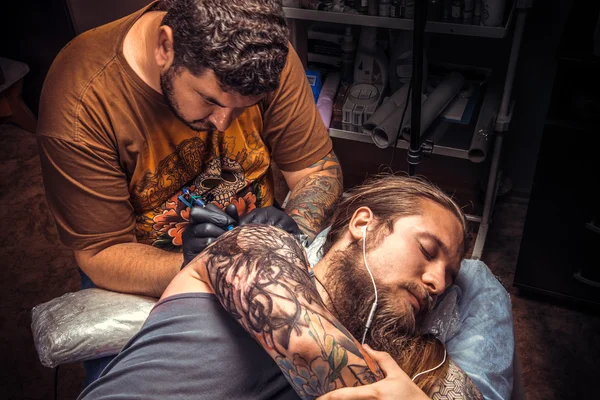 Man bär handskar gör cool tatuering i tatuerare — Stockfoto