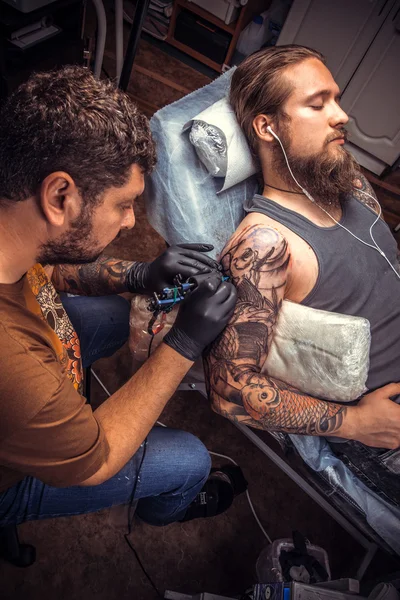 Az ember visel kesztyűt teszi jó tetoválás, tetováló szalon — Stock Fotó