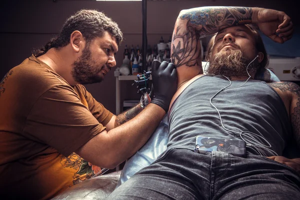 Homem usando luvas faz imagens de tatuagem no estúdio de tatuagem — Fotografia de Stock
