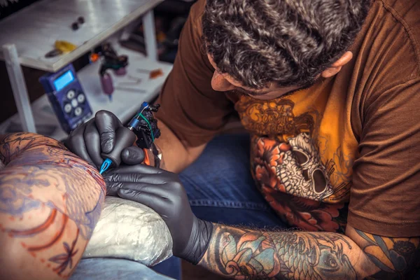 Az ember visel kesztyűt dolgozó tetoválás tattoo studio — Stock Fotó