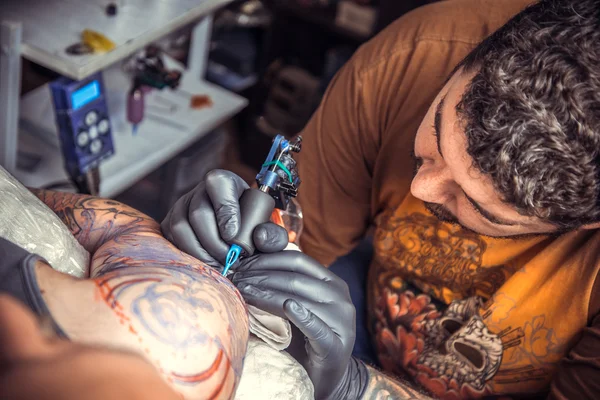 Професійний татуїст, що показує процес створення татуювання в салоні тату — стокове фото