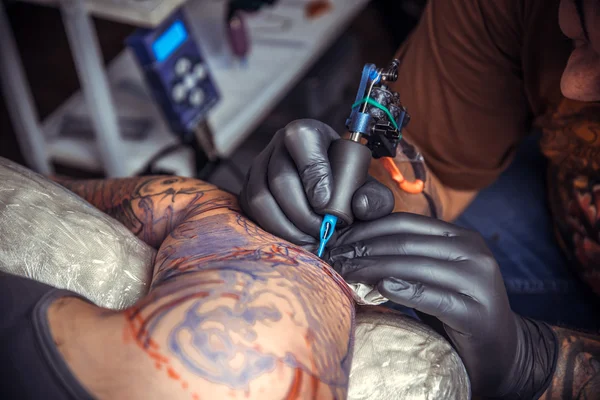 Tattoo specialist makes tattoo pictures in tattoo parlor — Stock Photo, Image