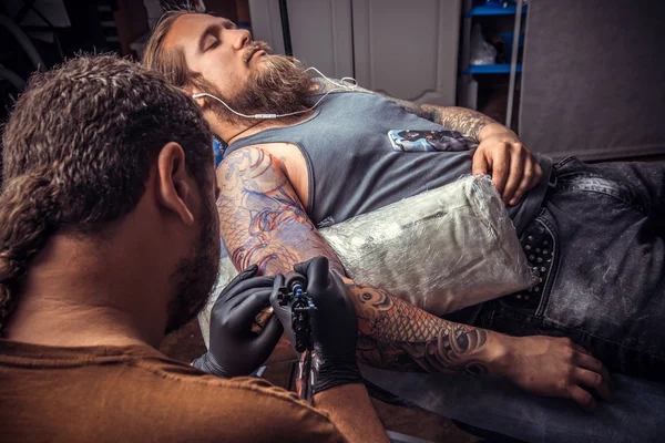Чоловік в рукавичках створює татуювання в салоні — стокове фото