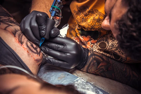 Мастер татуировки за работой в студии татуировки — стоковое фото