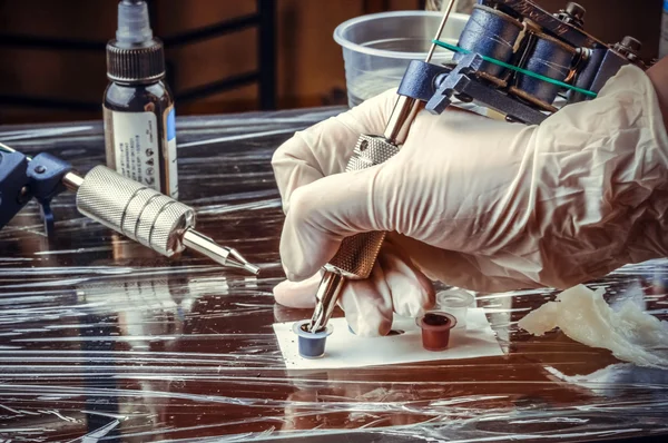 Tattooer showing process of making a tattoo in tatoo salon — Stock Photo, Image