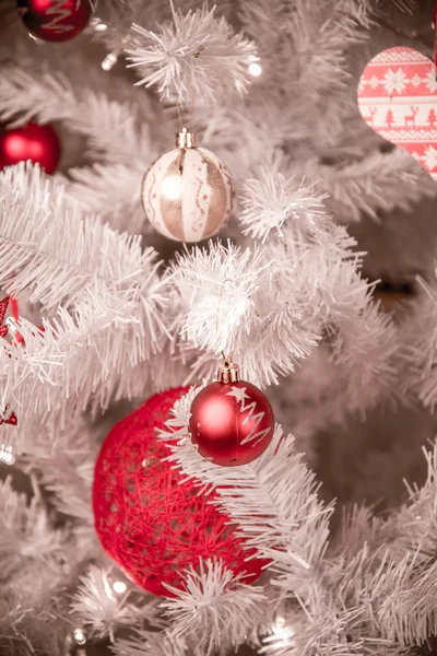 Closeup of red bauble hanging from a decorated Christmas tree Stock Photo