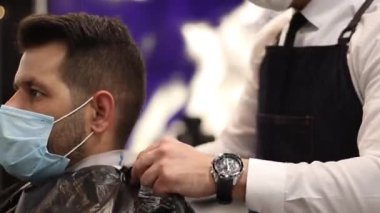 Genç berber müşteriyi saçtan korur.