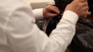 Papyon takmış eski berber ve pantolon askısı bir müşteriye pelerin takar..