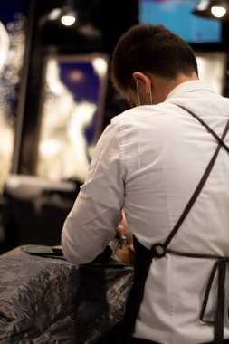 bilinmeyen berber saç kesim makinesiyle bir müşterinin sakalını kesiyor.