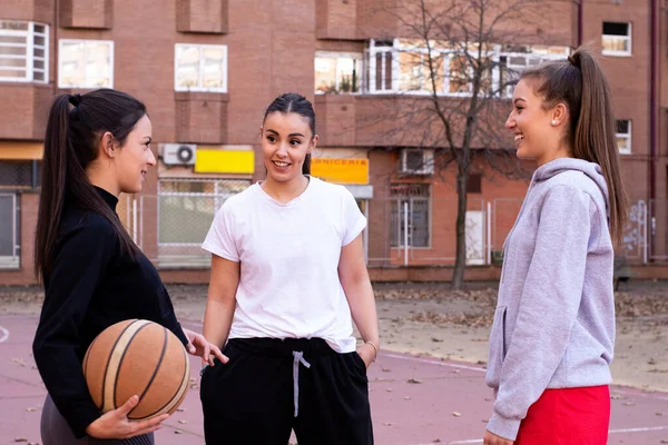 バスケットボールの試合前に3人の若いバスケットボール選手が都会のコートで交流する — ストック写真