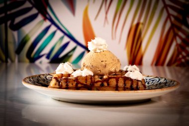 Lezzetli Waffle 'ı bir top dondurmayla süslenmiş karamel ile kapat. Arka plan renkli bitkilerle dolu..