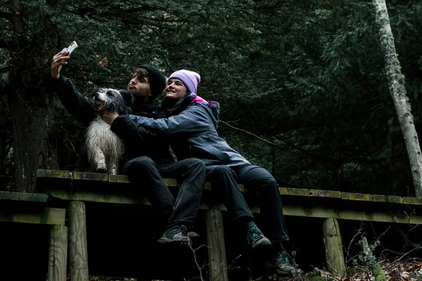 Młoda Para Siedzi Robi Sobie Selfie Drewnianej Drodze Lesie Obok — Zdjęcie stockowe
