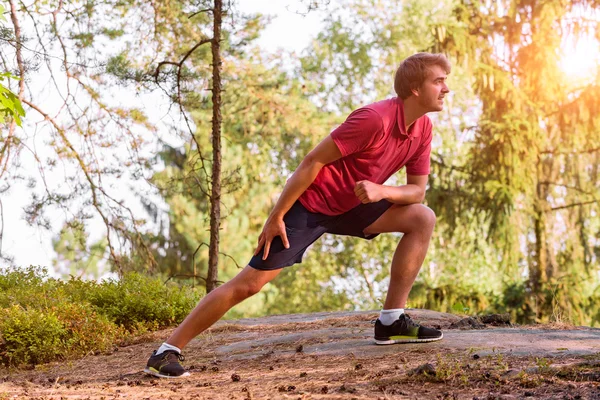 Jonge man die zich uitstrekt voordat joggen, kruis land loper — Stockfoto