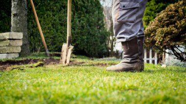 Eski çim kazmak için kürek kullanan adam