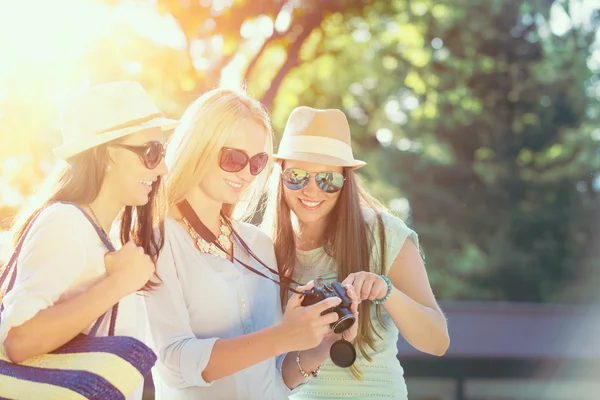 Tres chicas atractivas mirando fotos en su cámara en las vacaciones de verano, amigas en sus vacaciones de viaje — Foto de Stock