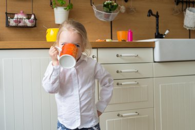 Sevimli sarışın kız mutfakta büyük bir fincan çay holding