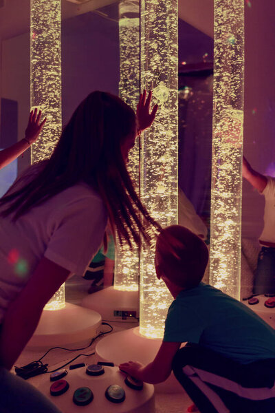 Special needs child in sensory stimulating room, snoezelen. Autistic child interacting with therapist during therapy session.