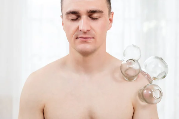 Young Man Getting Vacuum Cupping Treatment At a Spa. Vacuum Cupping Therapy. Treatment used in Traditional Chinese Medicine for pain relief and other health benefits.