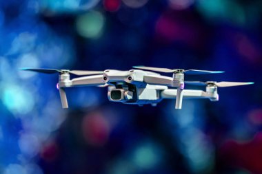 Uçan bir dron. Hava indirme kuadkopteri. İnsansız hava aracı ya da insansız hava aracı olarak da bilinir. Fotokopi alanı olan renkli bir arkaplanda kameralı Drone.