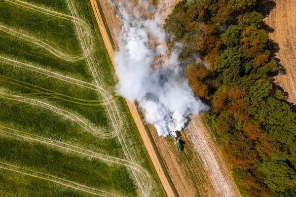 Aerial view of a tractor spreading lime on agricultural fields to improve soil quality after the autumn harvest. The use of lime powder to neutralize the acidity of the soil. 
