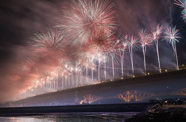 Группа людей смотрит фейерверк над мостом Форт Роуд, Эдинбург, Шотландия, Великобритания — стоковое фото
