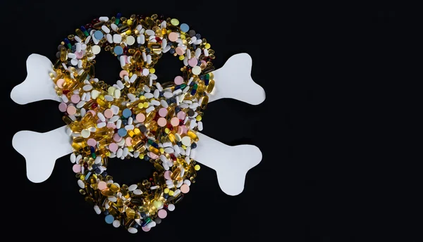Comprimés, pilules et capsules, qui forment un crâne effrayant., isolé sur fond noir — Photo