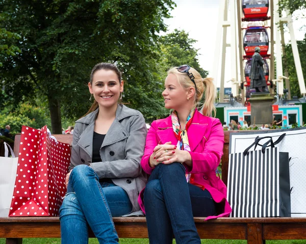 Two attractive young female friends enjoying a day out after successful shopping — Stock Photo, Image