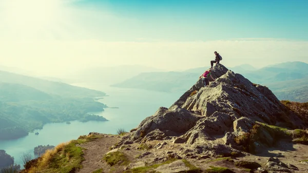 Two female hikers on top of the mountain enjoying valley view, Ben A'an, Loch Katrina, Highlands, Scotland, UK