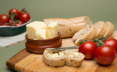 Ekmek ve tereyağı, ahşap tahta üzerinde olgunlaşmış domates ile lezzetli organik ev yapımı ekmek ve tereyağı