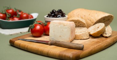 Ekmek ve peynir, lezzetli organik krem süt peynir, zeytin ve ev yapımı ekmek ve ahşap tahta üzerinde olgun domates