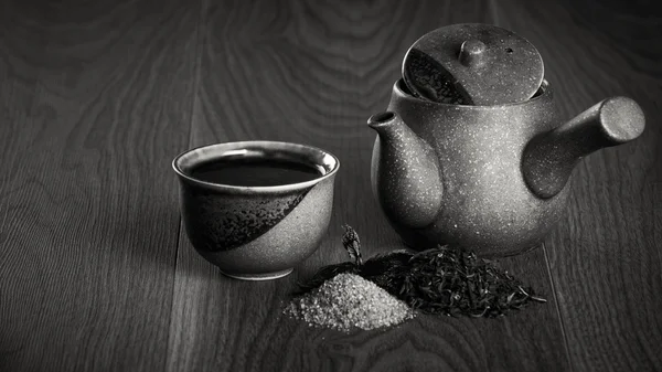 Ceramic teapot, cup of black tea with mint leaves and brown sugar on wooden table — Stock Photo, Image