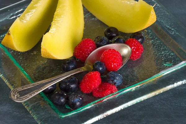Fruta fresca y saludable en un plato de postres de vidrio sobre fondo negro — Foto de Stock