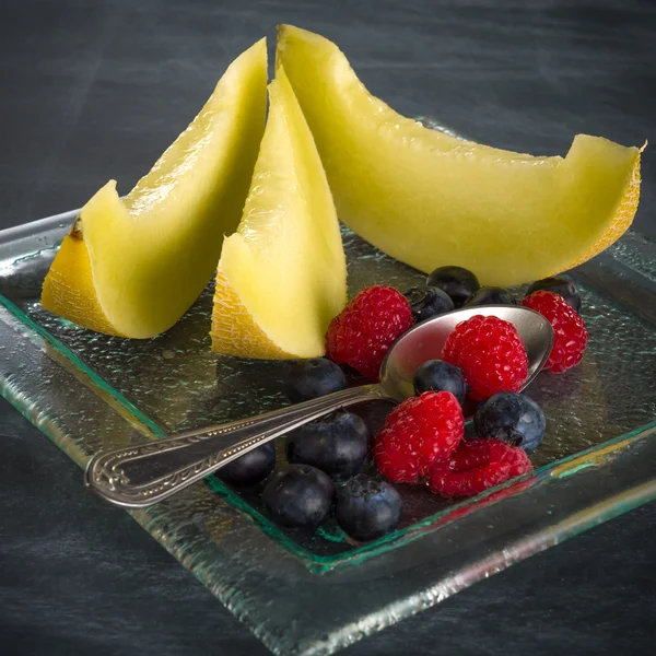 Fruta fresca y saludable en un plato de postres de vidrio sobre fondo negro — Foto de Stock