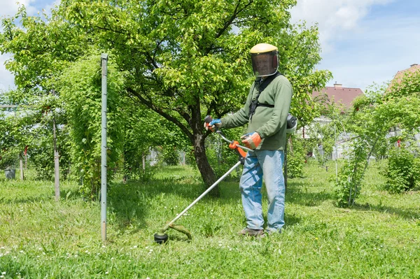 Male worker with power tool string lawn trimmer mower cutting grass — Stock Photo, Image