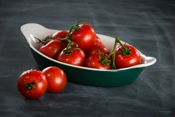 Reife Kirschtomaten in einer Schüssel auf schwarzem Hintergrund — Stockfoto