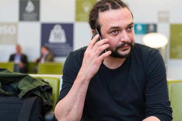 Yakışıklı genç bir Havaalanı lounge telefonunu kullanarak dreadlocks ile. — Stok fotoğraf