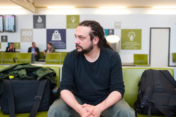 Handsome young man with dreadlocks waiting at an airport lounge. — Stock Photo, Image