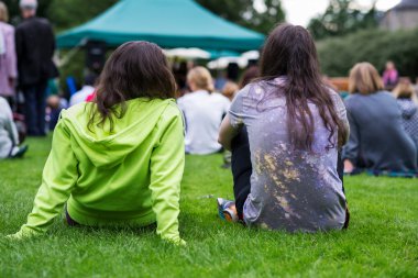 Bir açık havada müzik, alınan keyfi çimenlerin üzerinde oturan arkadaşlar