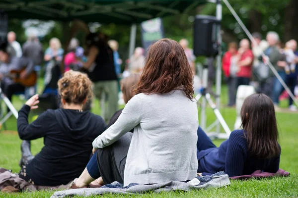 Przyjaciele siedząc na trawie, na zewnątrz muzyce, kulturze — Zdjęcie stockowe