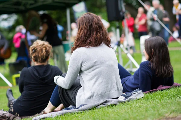 Amigos sentados en el césped, disfrutando de una música al aire libre, cultura — Foto de Stock