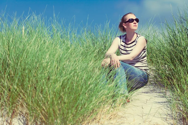 Jonge vrouw zitten in zandduinen onder hoog gras ontspannen, genieten van het uitzicht op zonnige dag, Luskentyre, Isle van Harris, Schotland — Stockfoto