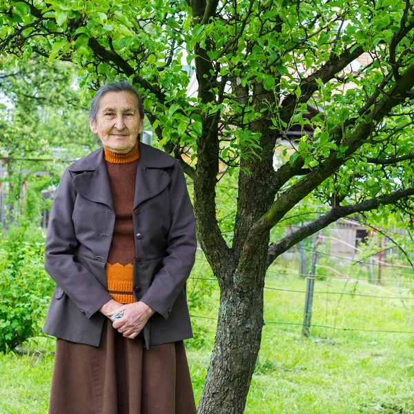 Vackra 80 plus år gammal senior kvinna poserar för ett porträtt i hennes trädgård. — Stockfoto