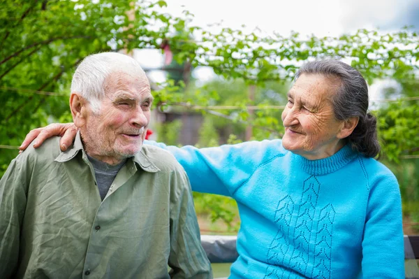 Söta 80 plus år gammal gift par poserar för ett porträtt i deras trädgård. Love forever koncept. — Stockfoto